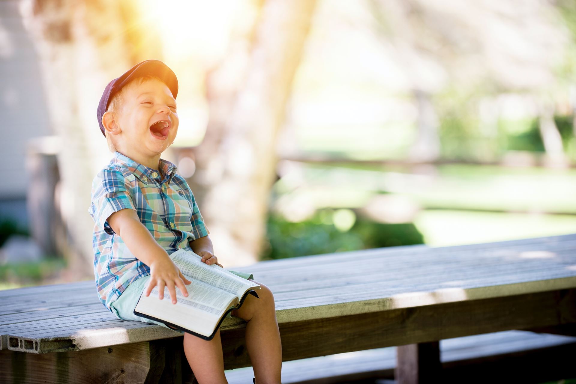 a child sat on a bench laughing while reading a book