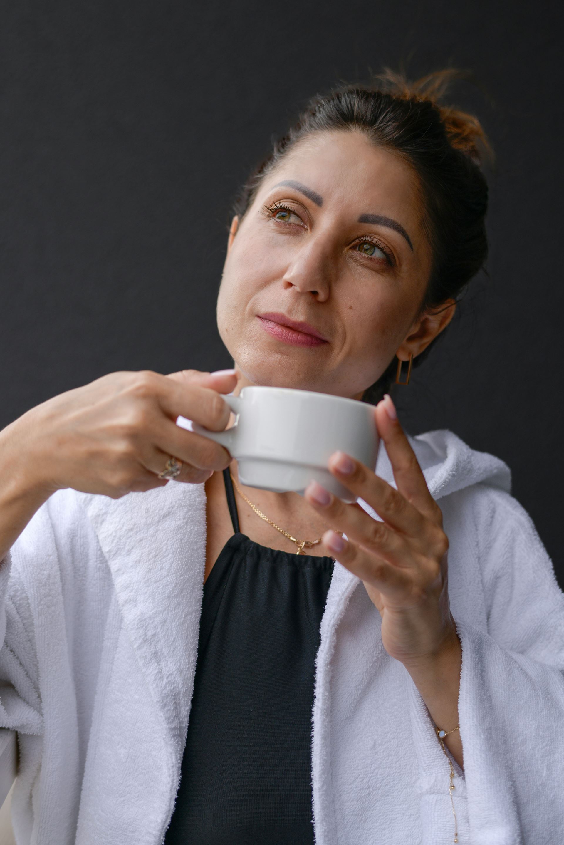 A woman drinking a cup of coffee and looking pensive